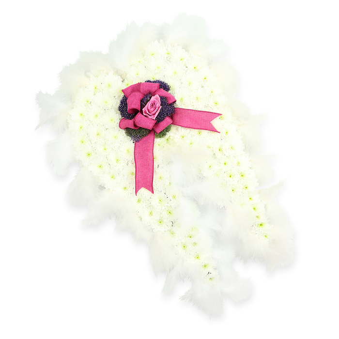 Captured against a pure white background, this angel wing-shaped funeral tribute radiates a quiet, heavenly calm. The wings are meticulously formed from hundreds of small white chrysanthemums, packed closely together so their petite petals interlock, creating a plush surface that looks as soft as a cushion of clouds. The faint green centres peeking from each bloom introduce a natural variation in tone, hinting at life and renewal within the serene white mass. Around the outer edge of the wings, a border of airy white feathers is carefully layered, each feather light and slightly curved, imitating genuine plumage and emphasising the winged silhouette. At the centre, where the two wings meet like hands folded in prayer, a vivid fuchsia-pink satin bow becomes the central ornament. Its loops are generous and rounded, and the trailing ribbons drift gracefully over the floral surface, breaking the white with a note of vibrant, heartfelt colour. Nestled in the heart of the bow is a single, beautifully formed pink rosebud, its petals gently enfolding one another as if protecting a cherished secret. Around this rose, a ring of dark purple, thistle-like blossoms or textured foliage adds depth, drawing the gaze inward and creating a thoughtful contrast. This angel wing design, at once delicate and strong, would sit gracefully at a funeral or memorial service in Feltham, on a stand beside the coffin or near the front of a chapel, quietly offering the message that a loved one is now watched over and carried on unseen wings.